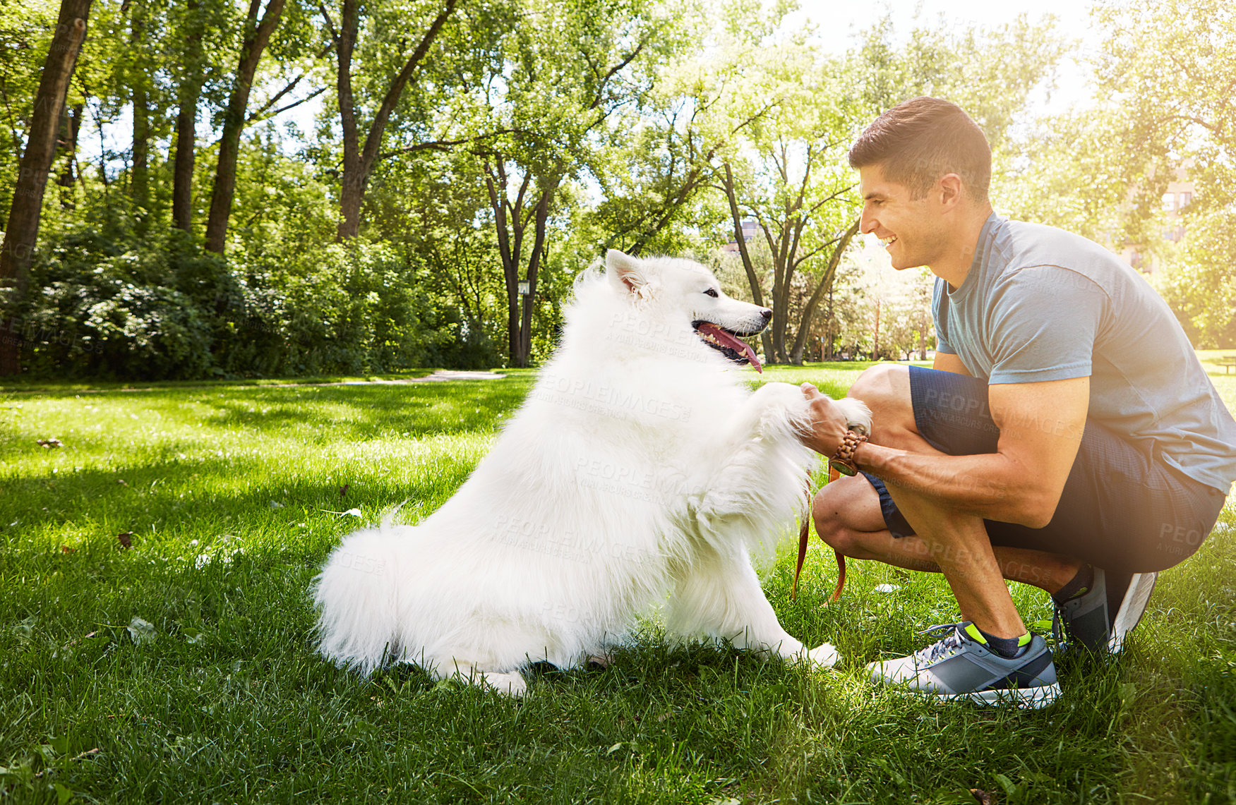 Buy stock photo Shot of a handsome young man walking his dog in the park