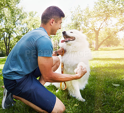 Buy stock photo Shot of a handsome young man walking his dog in the park