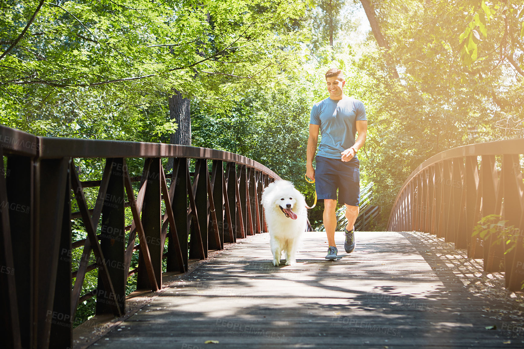 Buy stock photo Shot of a handsome young man walking his dog in the park