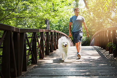 Buy stock photo Shot of a handsome young man walking his dog in the park