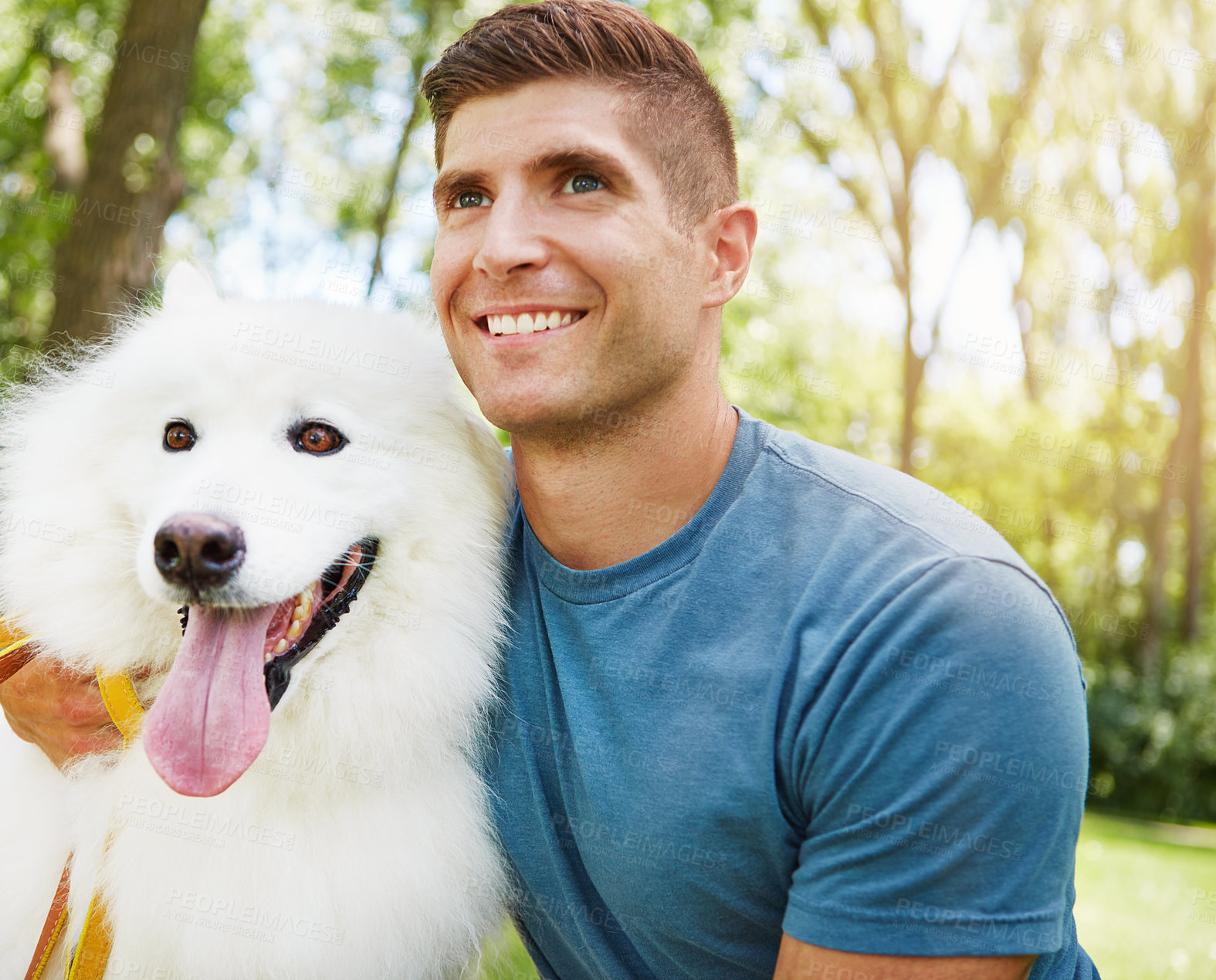 Buy stock photo Shot of a handsome young man walking his dog in the park