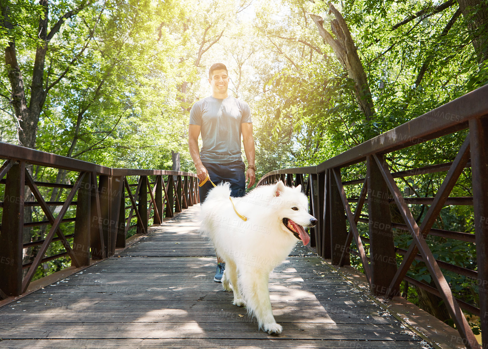 Buy stock photo Shot of a handsome young man walking his dog in the park