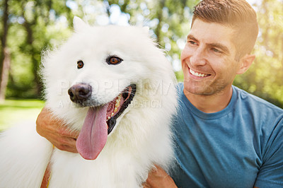 Buy stock photo Shot of a handsome young man walking his dog in the park