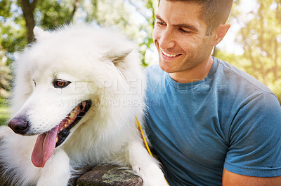 Buy stock photo Shot of a handsome young man walking his dog in the park