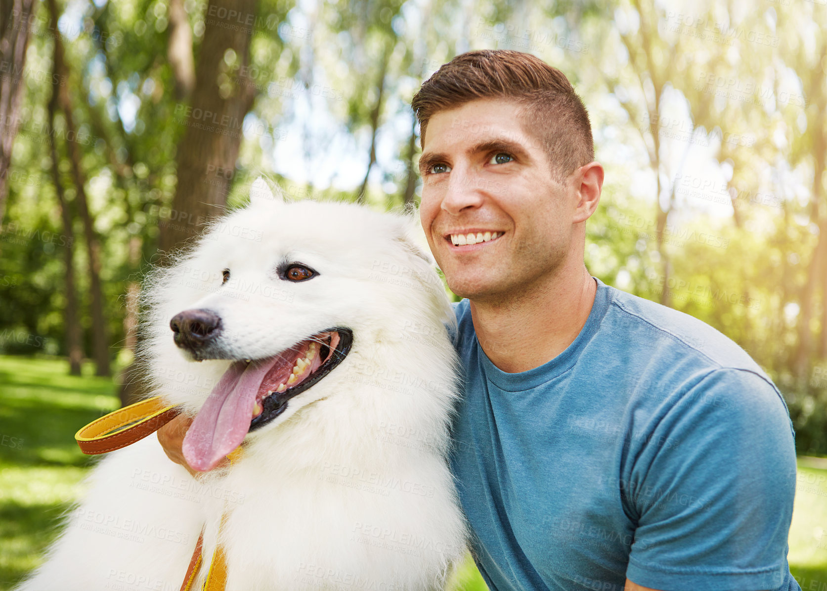 Buy stock photo Shot of a handsome young man walking his dog in the park