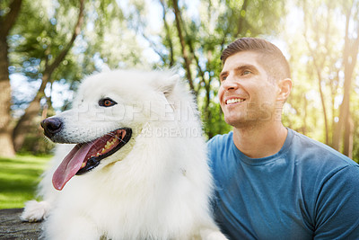 Buy stock photo Shot of a handsome young man walking his dog in the park