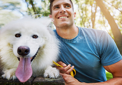 Buy stock photo Shot of a handsome young man walking his dog in the park