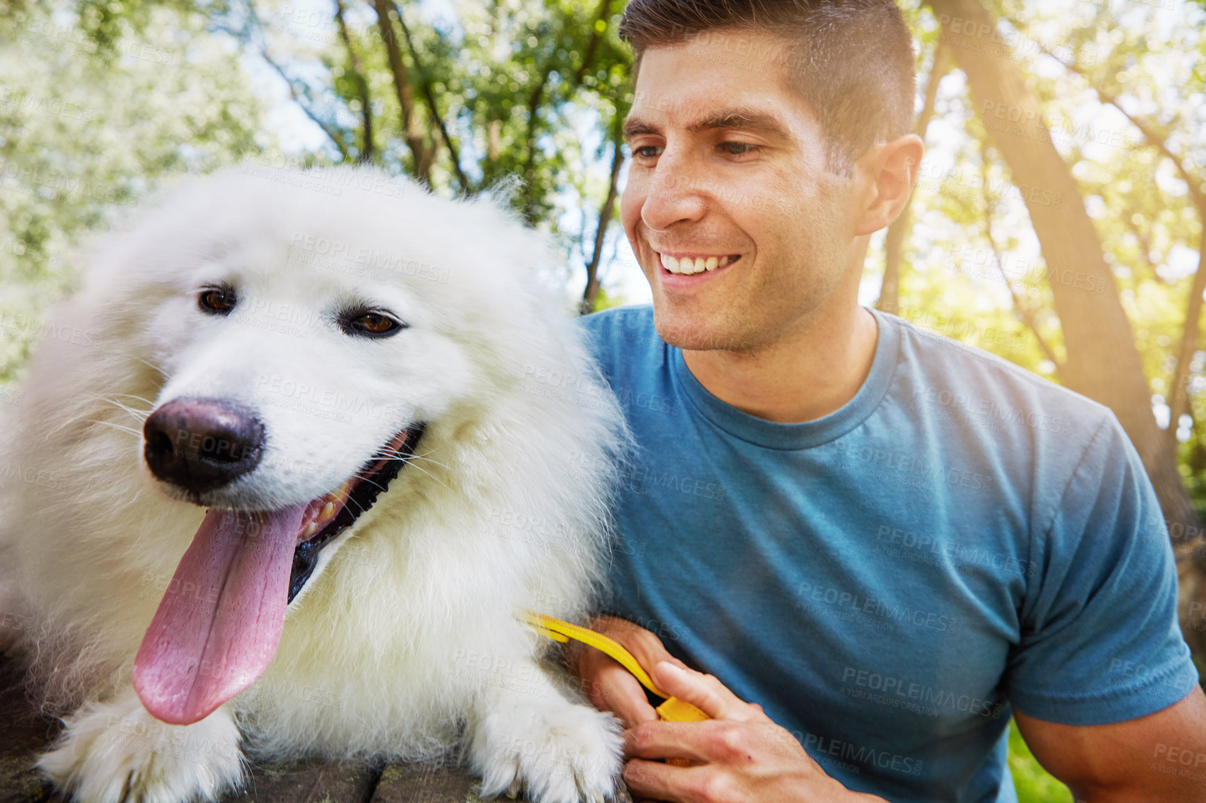 Buy stock photo Shot of a handsome young man walking his dog in the park