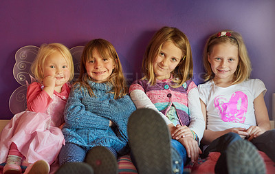 Buy stock photo Portrait of a group of little girls sitting together against a purple background