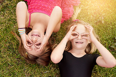 Buy stock photo Portrait of two little girls having fun while lying on the grass outside