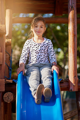 Buy stock photo Portrait of a little girl playing on a slide at the park