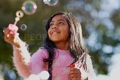 Buy stock photo Cropped shot of a little girl blowing bubbles outside