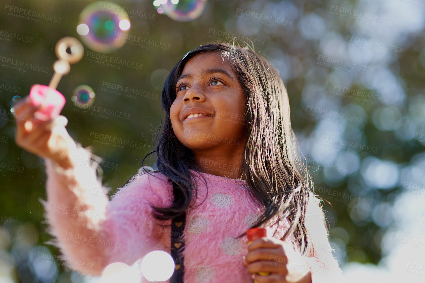 Buy stock photo Happy, outdoor and bubbles in nature park with girl, playful and curious by a tree. Child, freedom and outside from India feeling relax for smile in the spring, sunshine and games or fun in summer 


