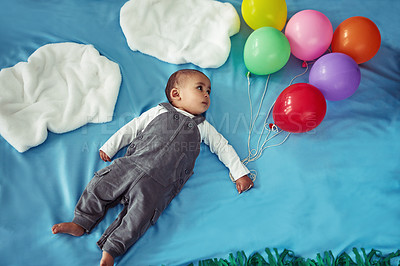 Buy stock photo Concept shot of an adorable baby boy flying through the sky holding a bunch of balloons