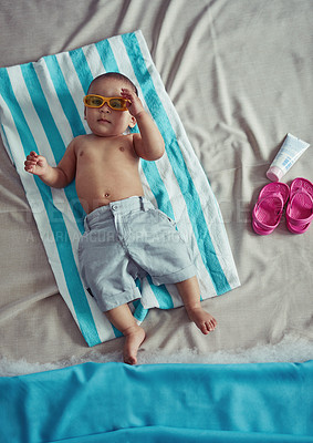 Buy stock photo Concept shot of an adorable baby boy lying on a towel at a make believe beach