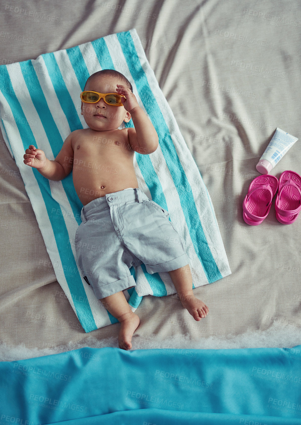 Buy stock photo Concept shot of an adorable baby boy lying on a towel at a make believe beach