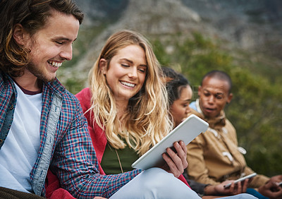 Buy stock photo Shot of a young man showing his tablet to a friend while they hang out outside