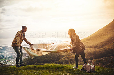 Buy stock photo Shot of two young friends setting up a picnic outside