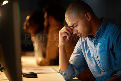Buy stock photo Cropped shot of a young businessman looking stressed out while working late in an office