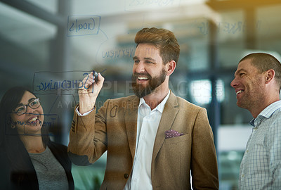 Buy stock photo Cropped shot of a group of colleagues brainstorming on a glass wall in an office