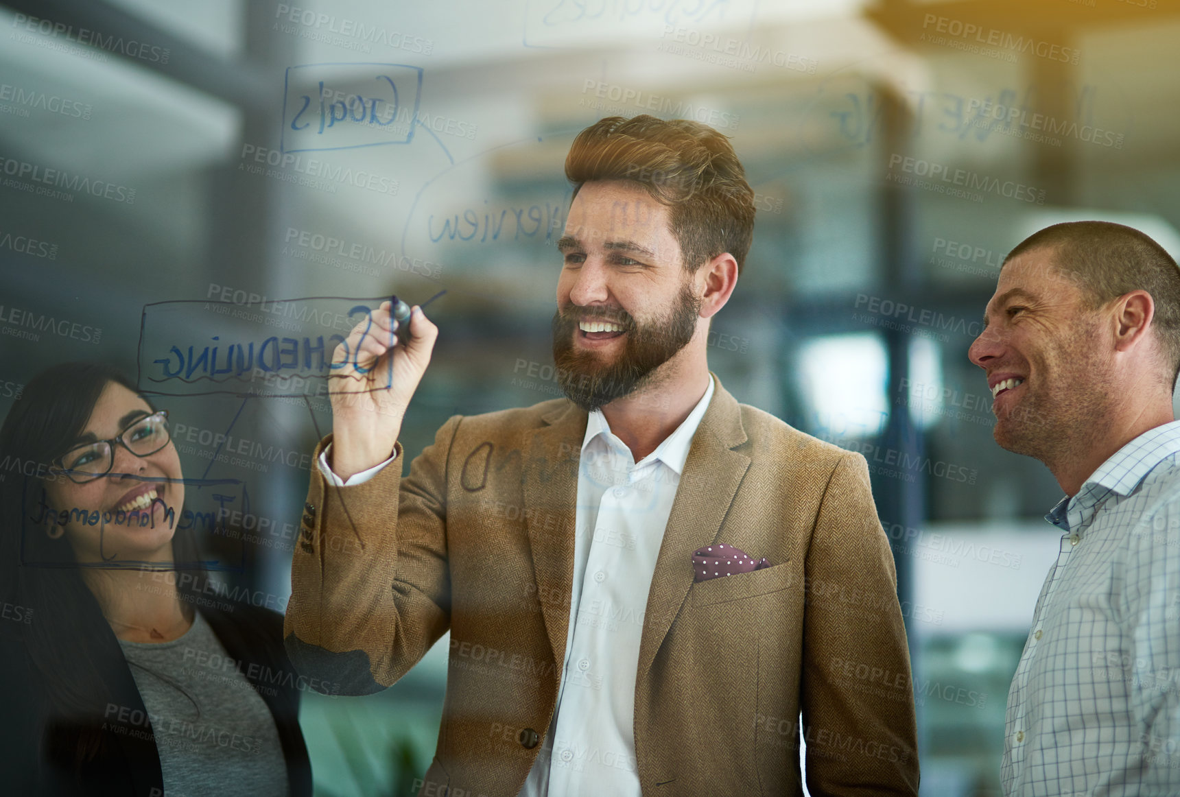 Buy stock photo Cropped shot of a group of colleagues brainstorming on a glass wall in an office