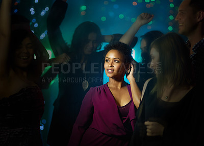 Buy stock photo Shot of a smiling young woman standing on a dance floor in a nightclub surrounded by people