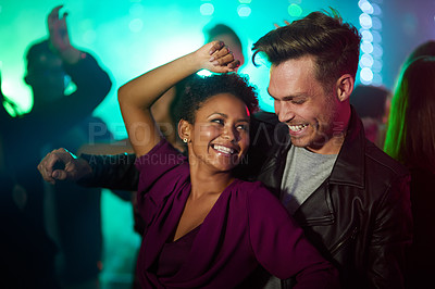 Buy stock photo Shot of a smiling young couple dancing together in a night club