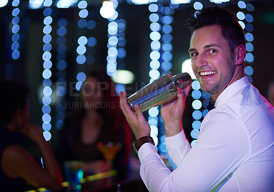 Buy stock photo Portrait of a smiling bartender mixing a drink behind the bar of a nightclub