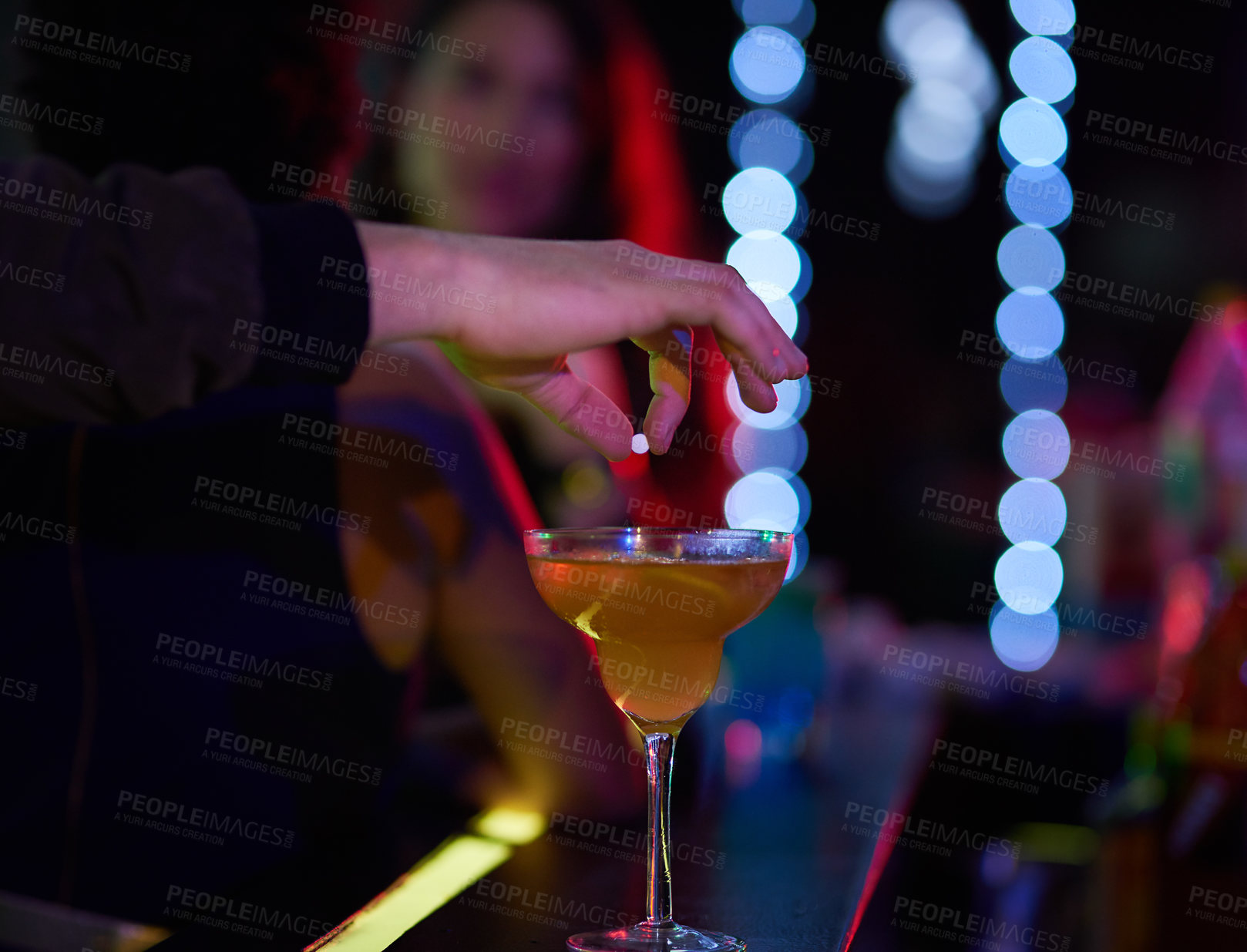 Buy stock photo Closeup shot of a man dropping a pill into a  woman's cocktail in a nightclub