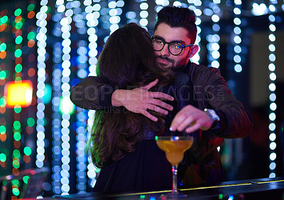 Buy stock photo Shot of a man dropping a pill into a  woman's cocktail behind her back in a nightclub