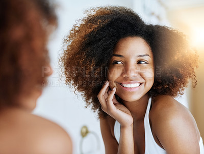 Buy stock photo Shot of an attractive young woman admiring her skin in front of the bathroom mirror