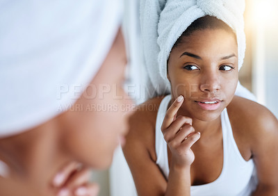 Buy stock photo Shot of a young woman inspecting her skin in front of the bathroom mirror