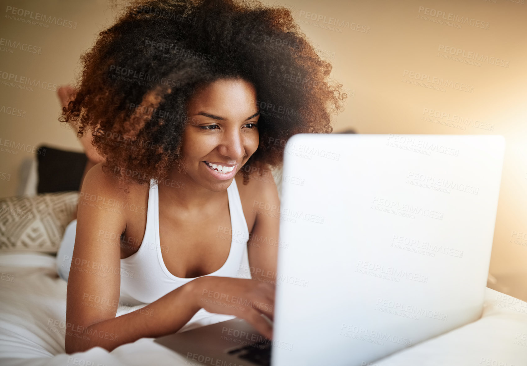 Buy stock photo Shot of a relaxed young woman using a laptop on her bed in the morning