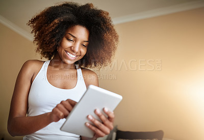 Buy stock photo Shot of a young woman using a digital tablet at home in the morning