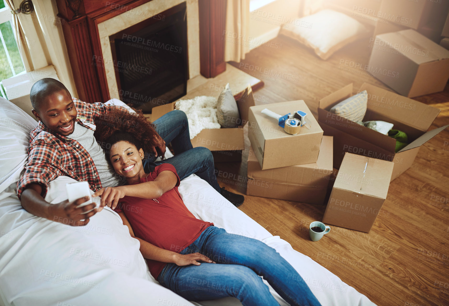 Buy stock photo Home, boxes and black couple on couch, smartphone and relaxing with social media, digital app and texting. Apartment, man or woman on sofa, cellphone and sunshine with internet, new house or marriage