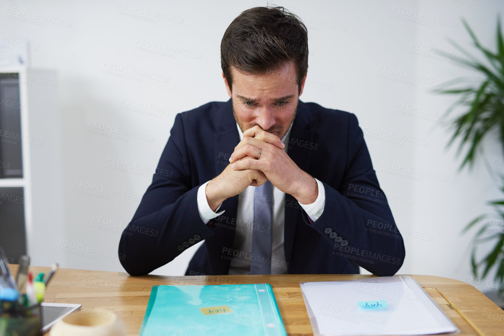 Buy stock photo Shot of a nervous looking businessman sitting at a desk trying to decide on which report to use
