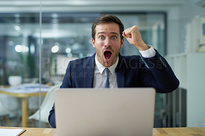 Buy stock photo Portrait of an angry businessman shouting and waving a fist while sitting at his laptop at a desk