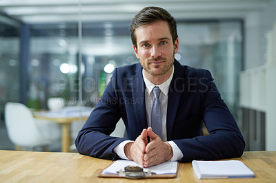 Buy stock photo Portrait of a confident young businessman sitting at a desk in an office
