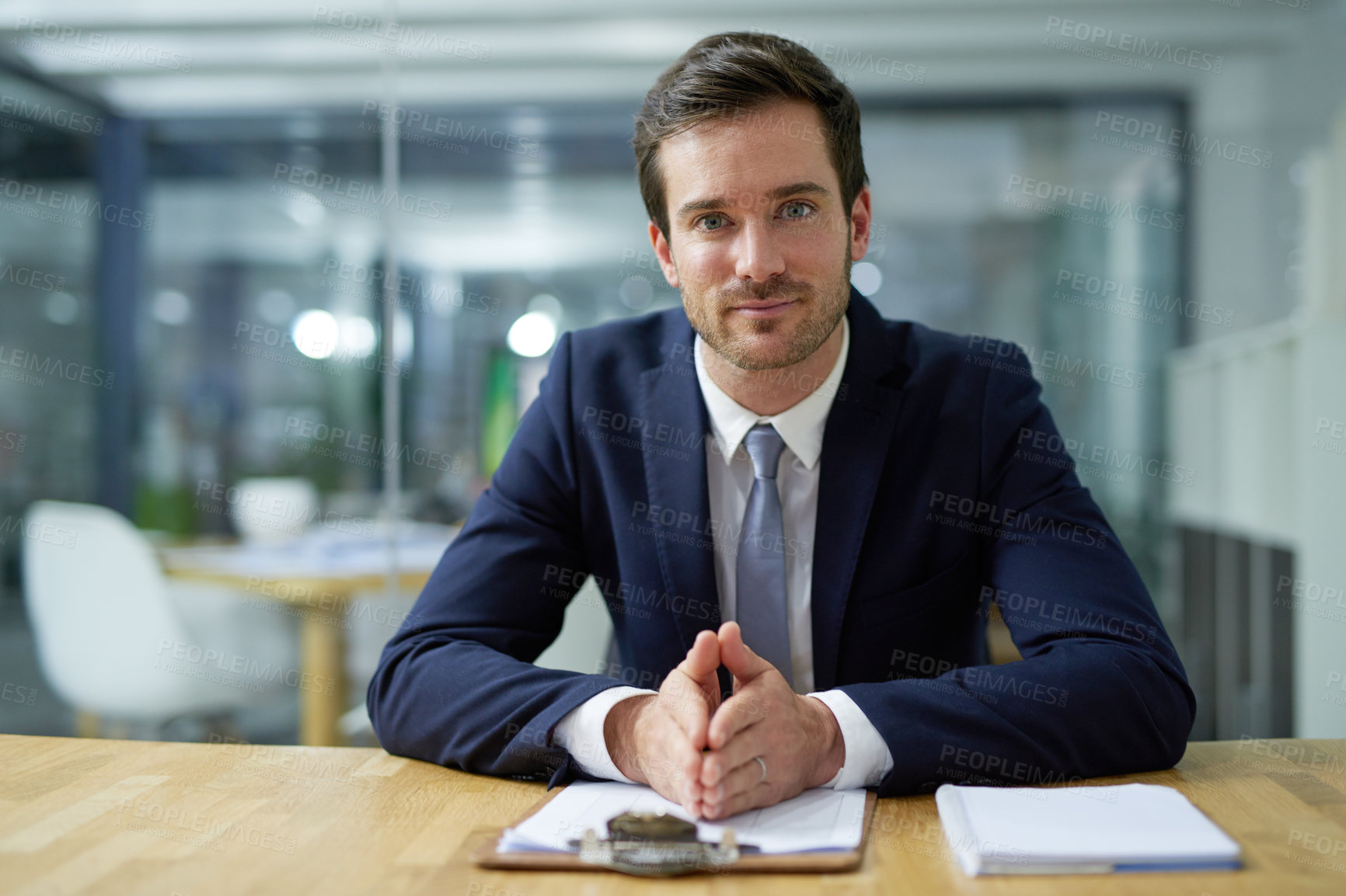 Buy stock photo Portrait of a confident young businessman sitting at a desk in an office