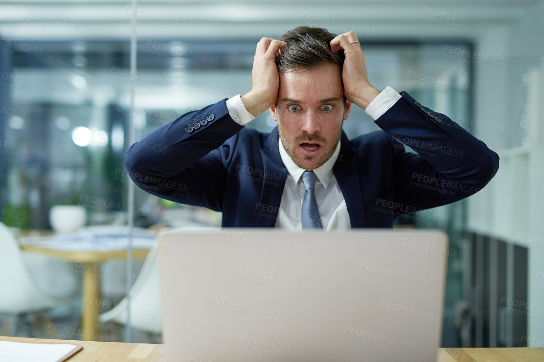 Buy stock photo Shot of a stressed out businessman sitting in shock while working on a laptop in an office