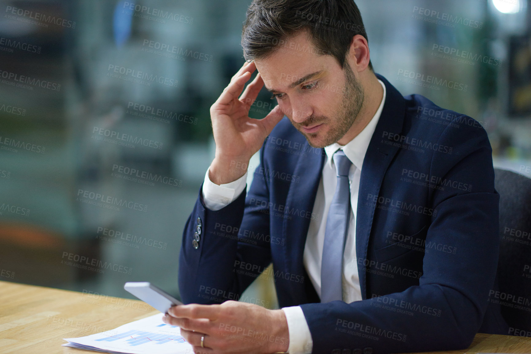 Buy stock photo Shot of a businessman using a cellphone while sitting at a desk in an office