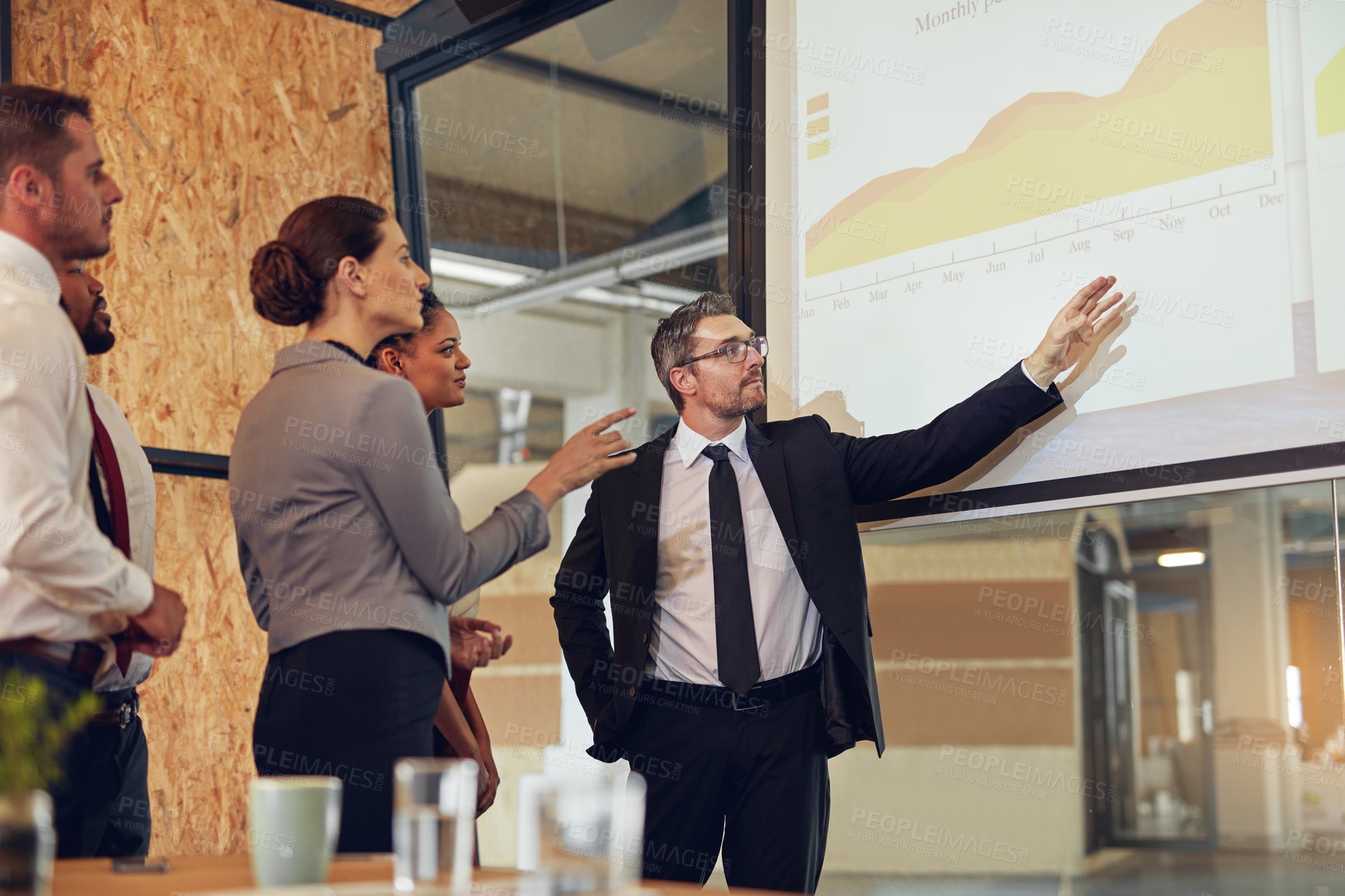 Buy stock photo Shot of an executive giving a presentation on a projection screen to a group of colleagues in a boardroom