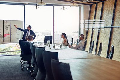 Buy stock photo Shot of an executive giving a whiteboard presentation to a group of colleagues in a boardroom
