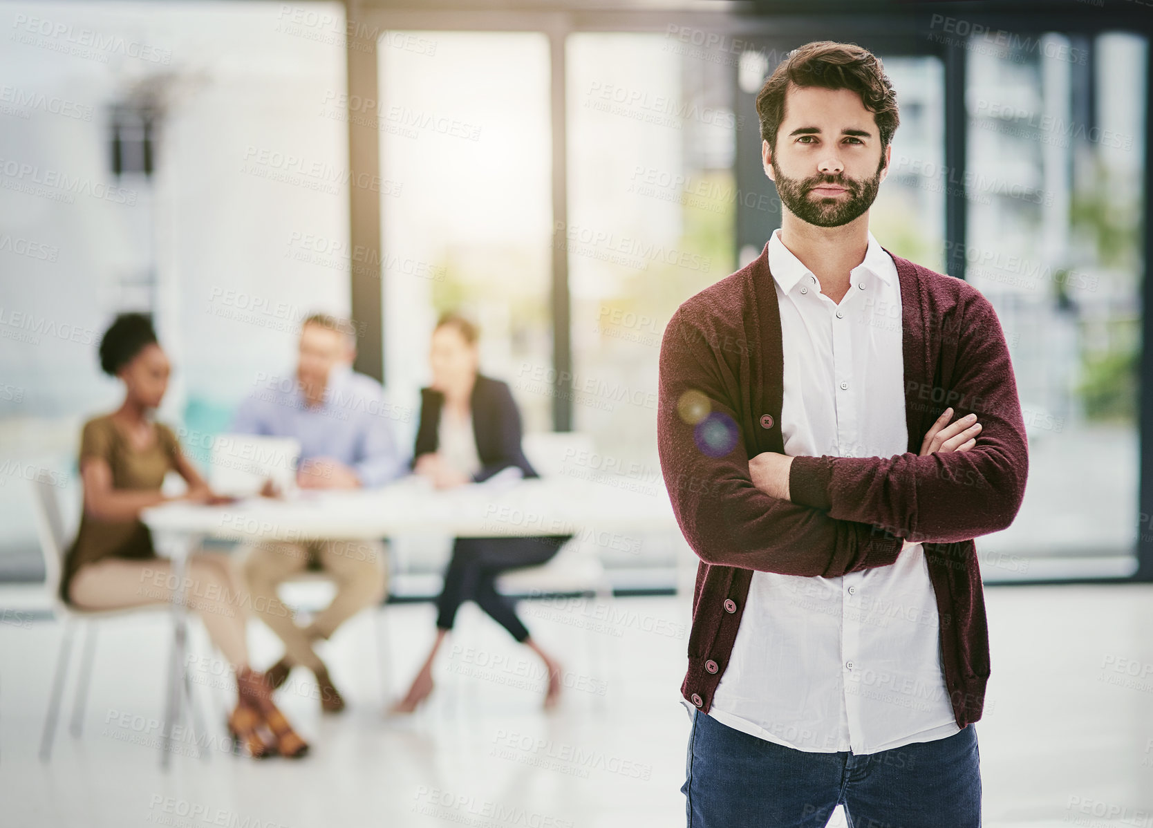 Buy stock photo Portrait of a young man standing in an office with colleagues meeting in the background