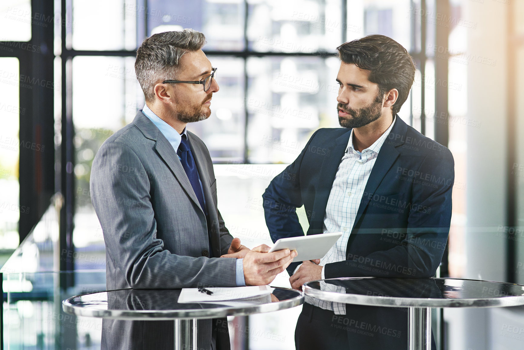 Buy stock photo Cropped shot of two businessmen working together on a digital tablet in an office