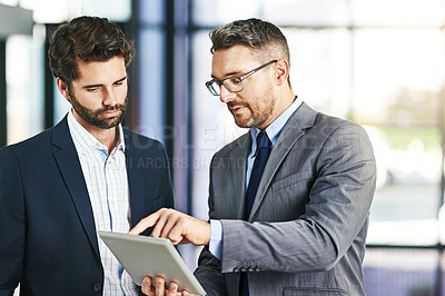 Buy stock photo Cropped shot of two businessmen working together on a digital tablet in an office