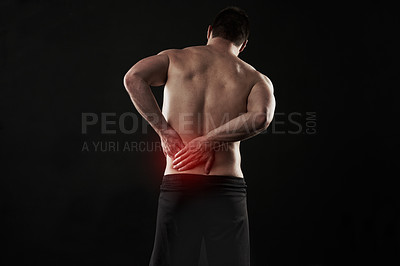 Buy stock photo Studio shot of a sporty young man suffering with back pain isolated on black