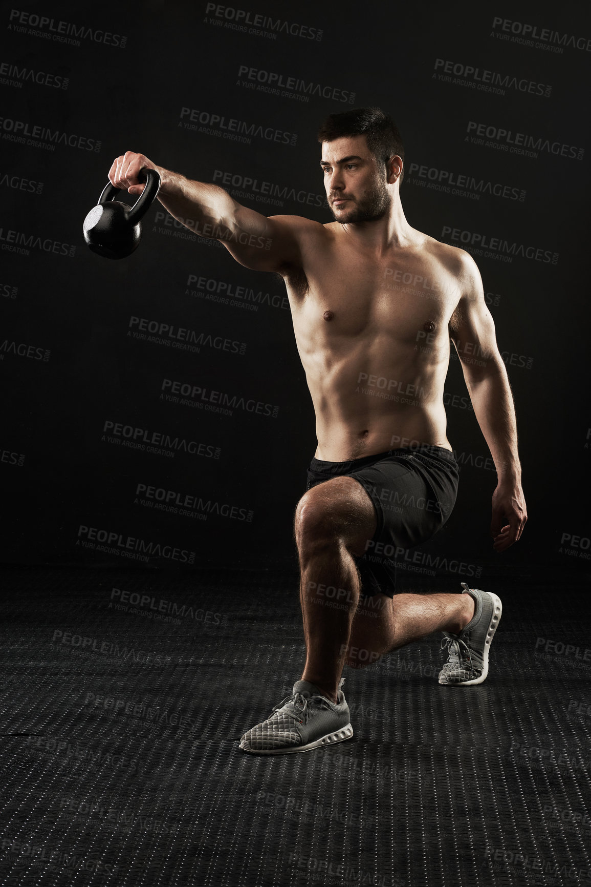 Buy stock photo Studio shot of a sporty young man working out with a kettle bell isolated on black