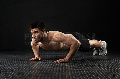 Buy stock photo Studio shot of a sporty young man doing push-ups isolated on black