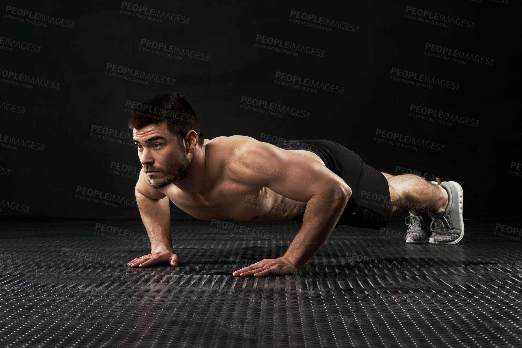 Buy stock photo Studio shot of a sporty young man doing push-ups isolated on black